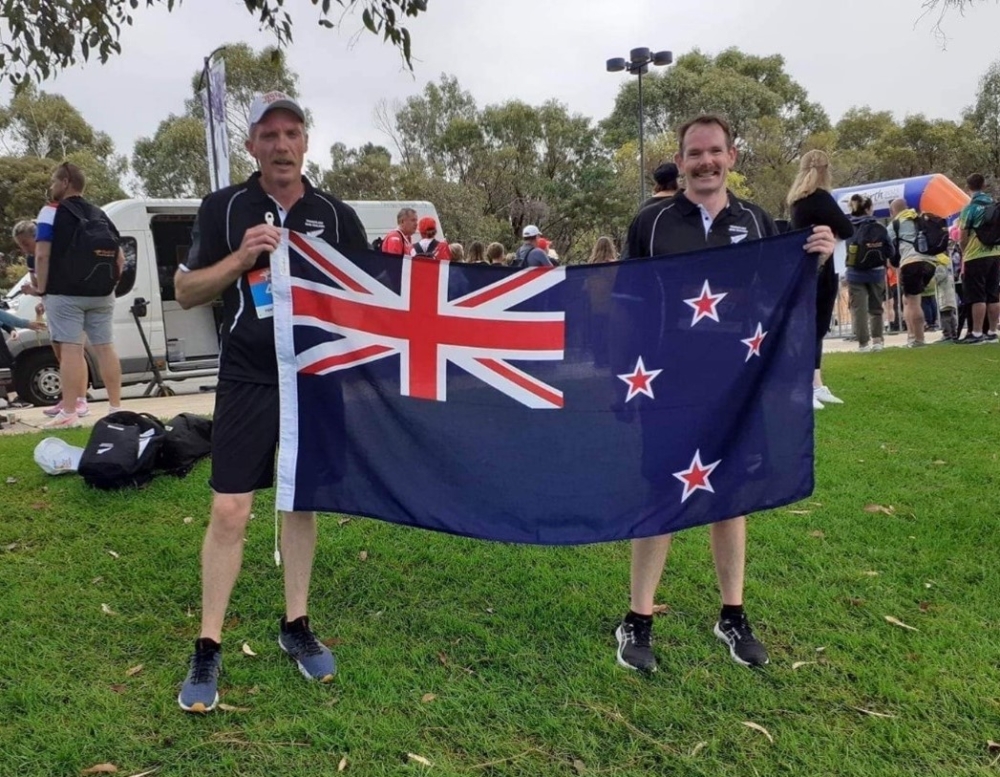 Two men holding a New Zealand Flag. 